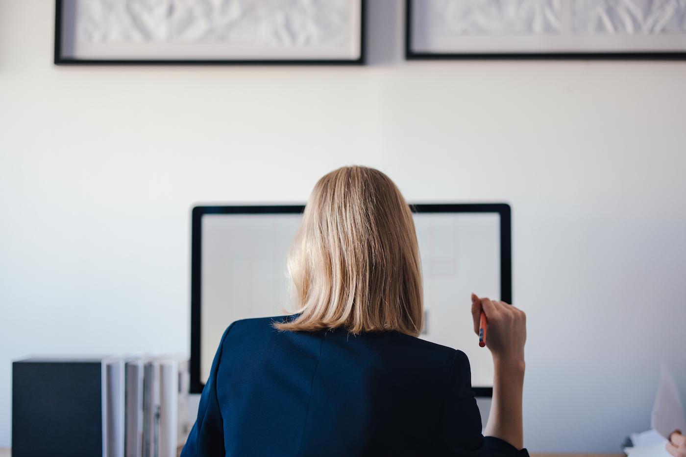 A business leader seated at her desk, facing a computer screen
